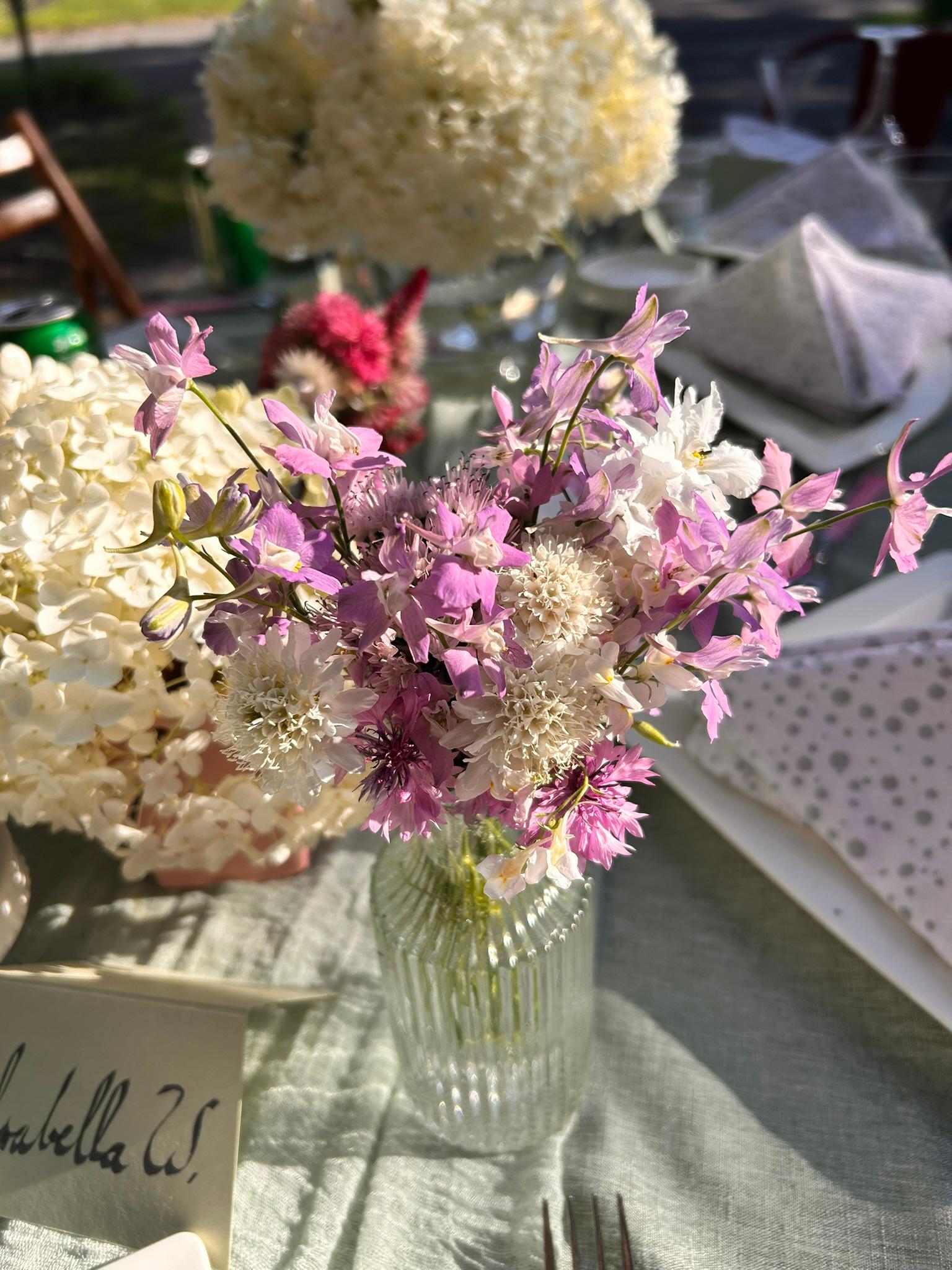 Fresh bouquet with pale pink, lavender, and white flowers arranged in a ribbed glass vase.