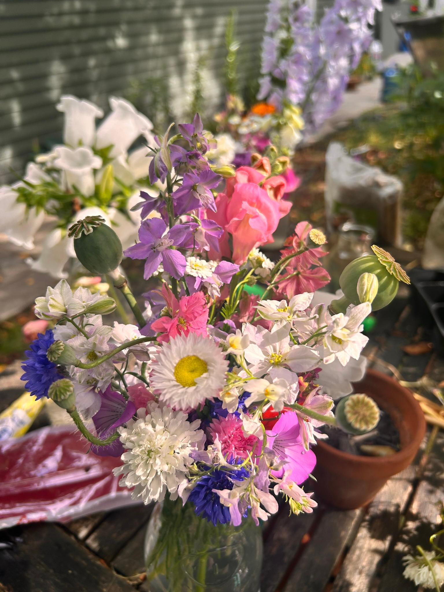 Pastel garden bouquet in a jar with pink, white, purple, and blue blooms.